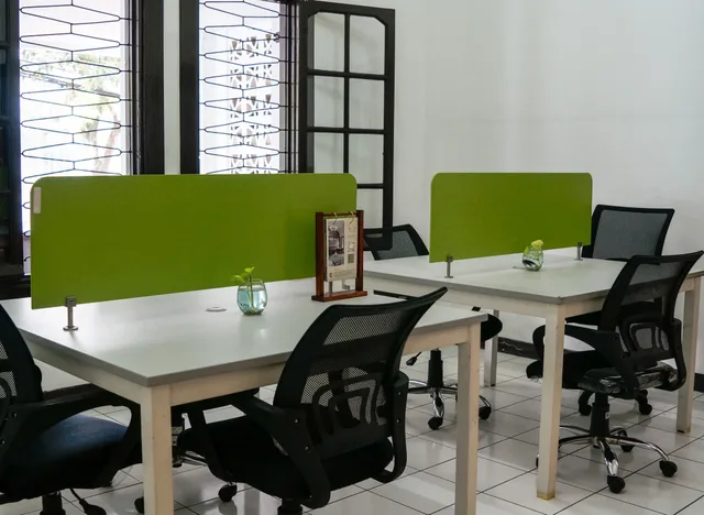 Neat and modern co-working office space featuring green dividers and ergonomic chairs. Silent workspace ideas grouped by the noise problem they solve